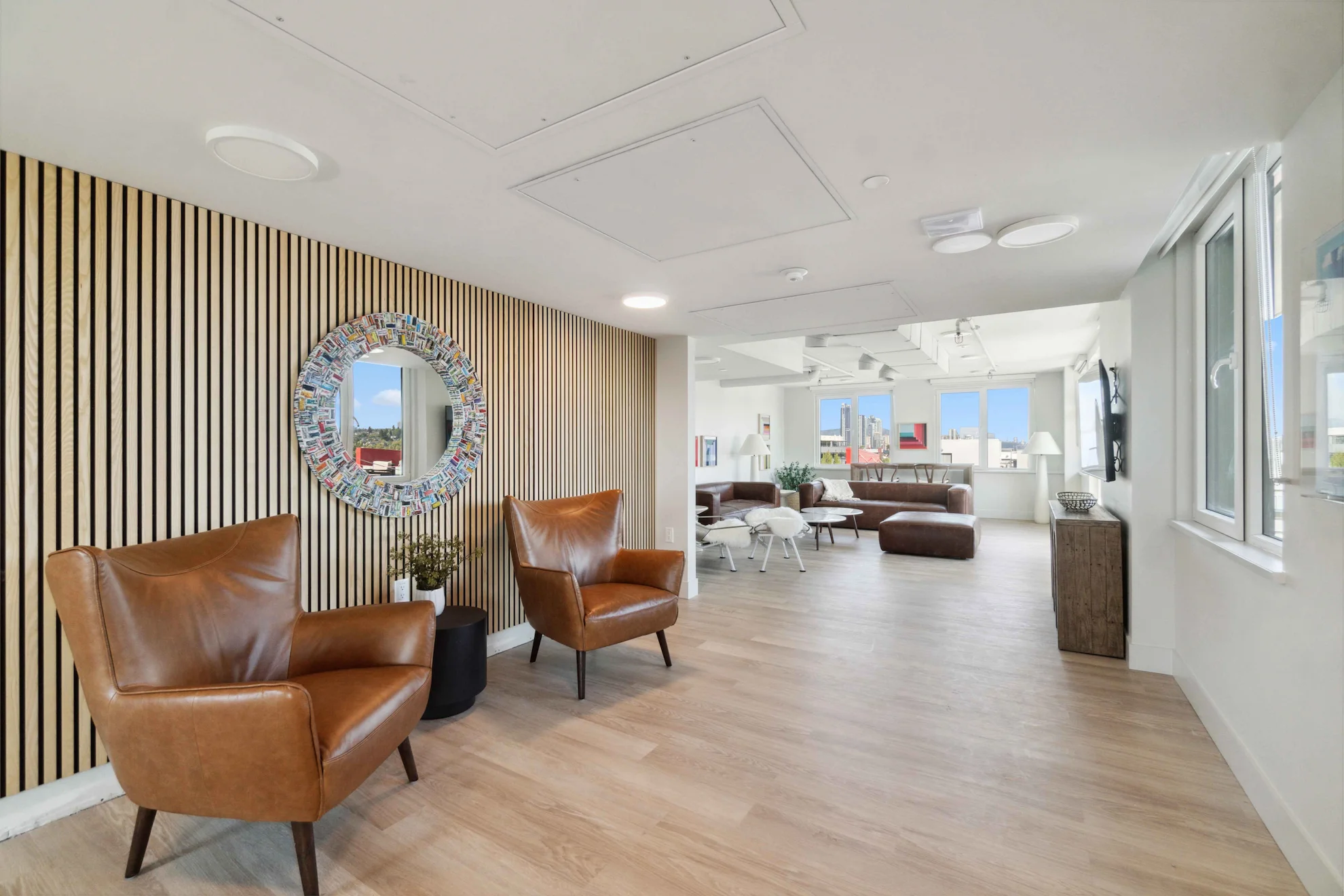 Stylish resident lounge with leather chairs, modern decor, and bright windows at Renfrew Village, perfect for relaxing or socializing.