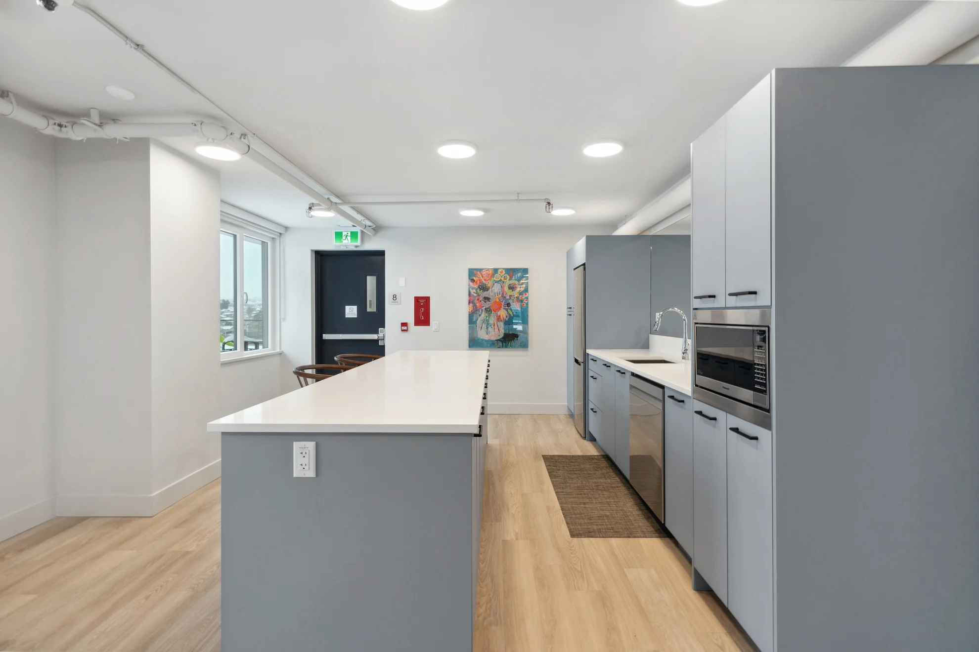 Sleek community kitchen with large island and stainless steel appliances at Renfrew Village, designed for convenience and social gatherings.